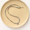 The sapphire and elephant necklace styled on a tan plate to show the adjustable lobster clasp closure
