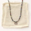 The sapphire and elephant necklace styled on tan linen