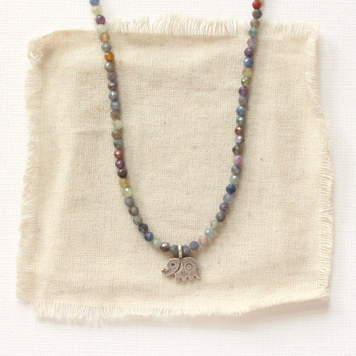 The sapphire and elephant necklace styled on tan linen