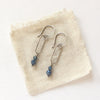The sapphire hoop earrings styled on tan linen