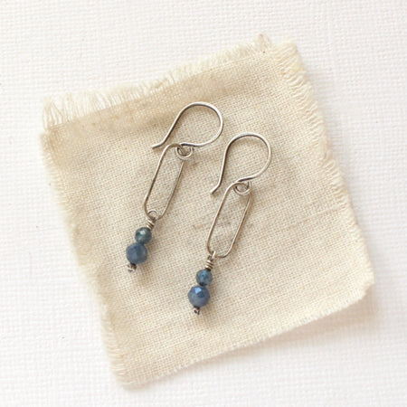 The sapphire hoop earrings styled on tan linen