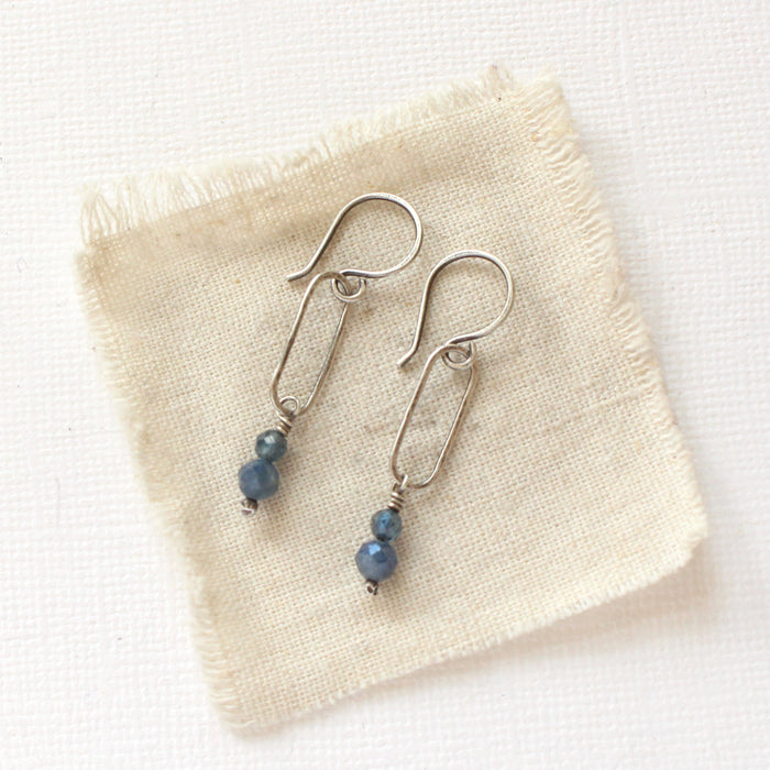 The sapphire hoop earrings styled on tan linen