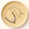 The bronze cactus flower vinca necklace styled on a tan plate to show the adjustable lobster clasp closure