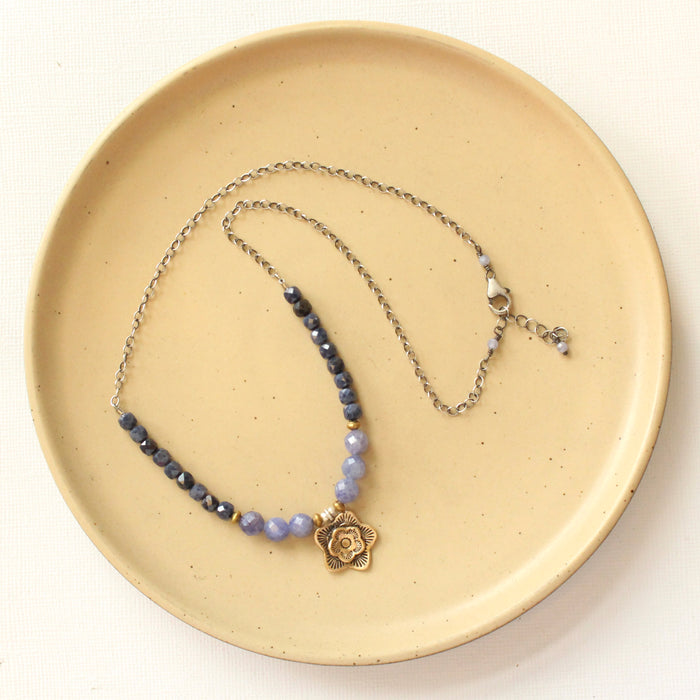 The bronze cactus flower vinca necklace styled on a tan plate to show the adjustable lobster clasp closure