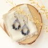 The vinca hoop earrings styled on wood with linen and dried grass