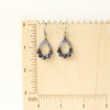 The vinca hoop earrings on a wooden ruler for size reference