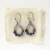 The vinca hoop earrings styled on tan linen