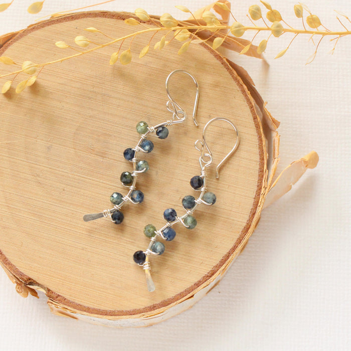 The sapphire wrapped silver vine earrings styled on wood with dried grass