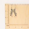 The sapphire wrapped silver vine earrings on a wooden ruler for size reference