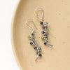 The sapphire wrapped silver vine earrings styled on a tan plate