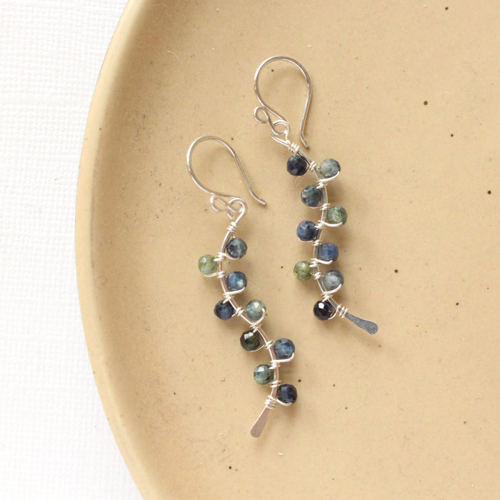 The sapphire wrapped silver vine earrings styled on a tan plate