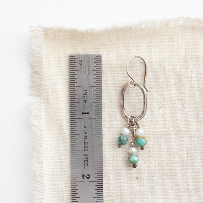 A seaside hoop earring next to a ruler for size reference