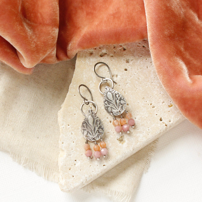 The shades of summer teardrop earrings styled on a white rock with linen and orange velvet