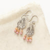 The shades of summer teardrop earrings styled on tan linen