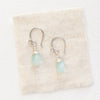 The chalcedony drop silver earrings styled on tan linen