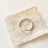 The silver momentum ring styled on tan linen to show the top view