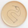 The silver open bar necklace styled on a tan plate to show the adjustable lobster clasp closure