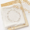 The silver paperclip styled on a tan rock with linen and dried grass