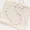 The bright silver paperclip necklace styled on tan linen