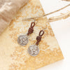 The silver wanderer coin leather earrings styled on a tan rock with velvet and dried grass
