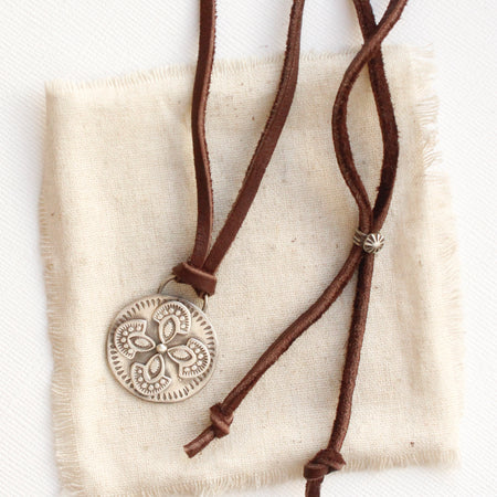 The silver wanderer medallion adjustable leather necklace styled on tan linen