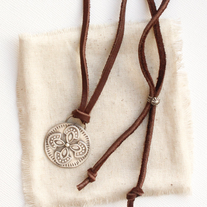 The silver wanderer medallion adjustable leather necklace styled on tan linen