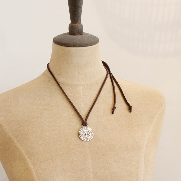 A mannequin wearing the silver wanderer medallion adjustable leather necklace in the short style