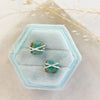 The silver wrapped turquoise square post earrings styled on a blue velvet box with linen and dried grass