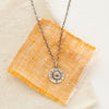 The small musana sun necklace styled on tan and orange linen