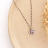 The small musana sun necklace styled on a tan plate with dried grass