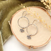The soar hoop earring styled on wood with green velvet and dried grass