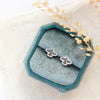 The soar post earrings styled on a blue velvet box with dried grass