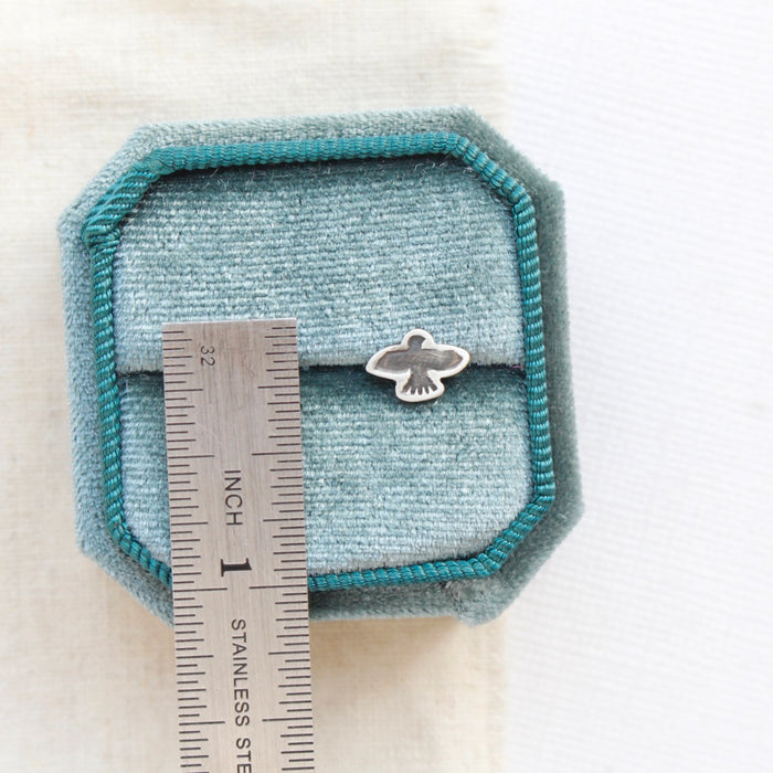 A soar post earring next to a ruler for size reference