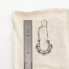 A speckled turquoise columbine hoop earring next to a ruler for size reference