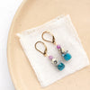 The stacked capri earrings styled on a tan plate with linen