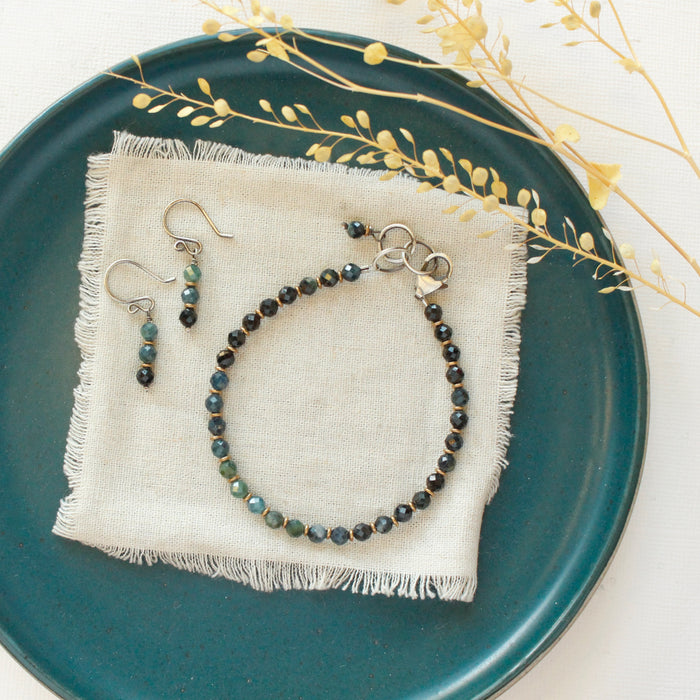 The stacked blue tourmaline earrings styled on a blue plate with the matching bracelet