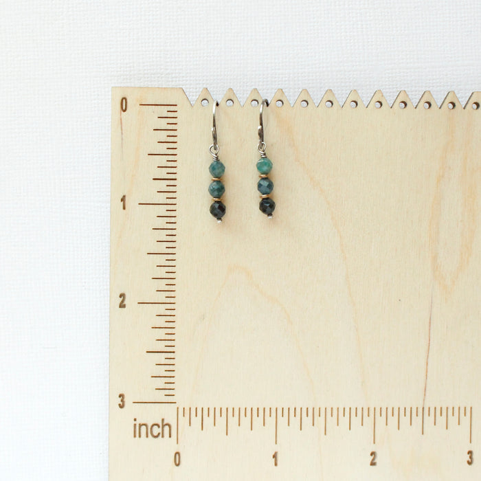 The stacked blue tourmaline earrings on a wooden ruler for size reference