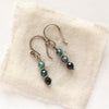 The stacked blue tourmaline earrings styled on tan linen