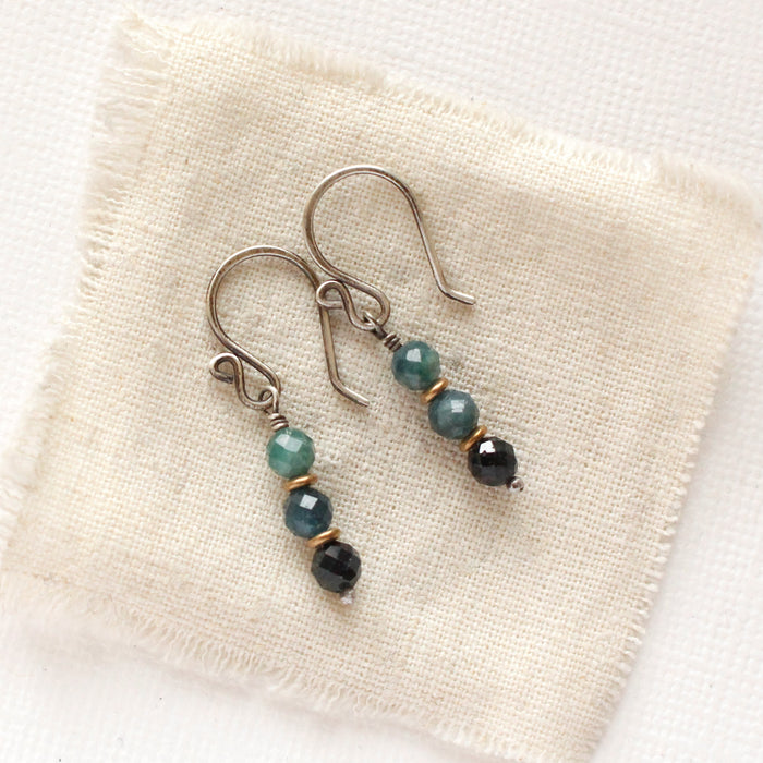 The stacked blue tourmaline earrings styled on tan linen