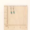 The stacked bondi earrings on a wooden ruler for size reference
