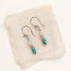 The stacked ethiopian opal, sunstone, and turquoise earrings styled on tan linen