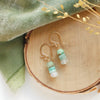 The stacked tide earrings styled on wood with green velvet and dried grass