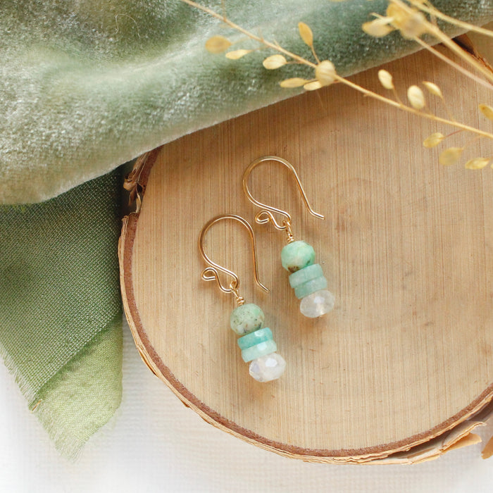 The stacked tide earrings styled on wood with green velvet and dried grass