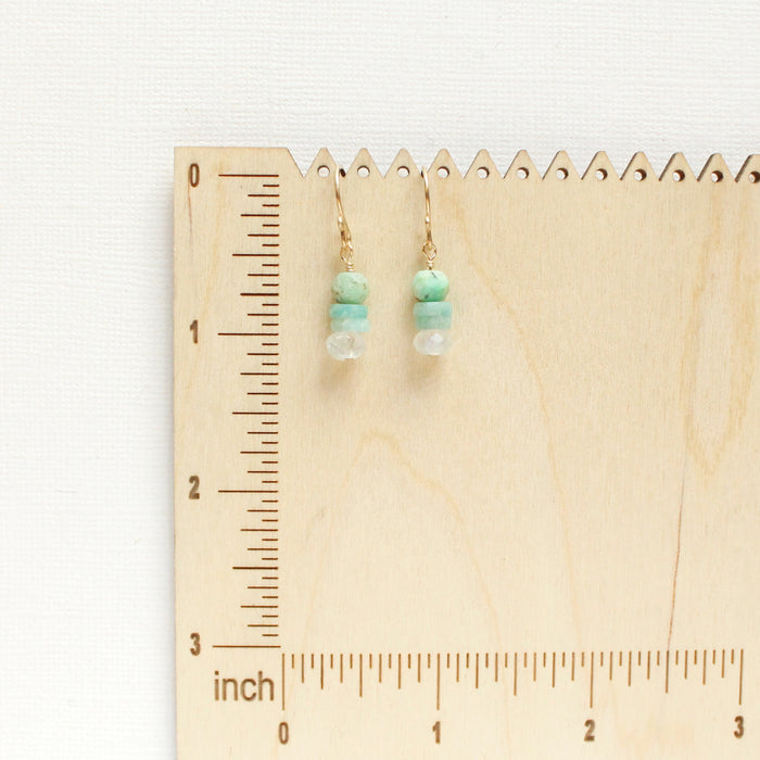 The stacked tide earrings on a wooden ruler for size reference