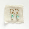 The stacked tide earrings styled on tan linen