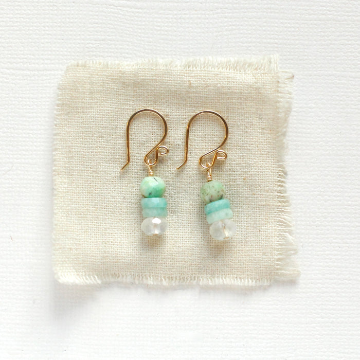 The stacked tide earrings styled on tan linen