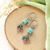 The colorful stacked elise earrings styled on wood with green velvet and dried grass