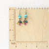 The stacked elise earrings on a wooden ruler for size reference
