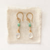 The stacked emerald and moonstone drops styled on tan linen