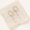 The stacked opal and pearl earrings in gold fill styled on tan linen